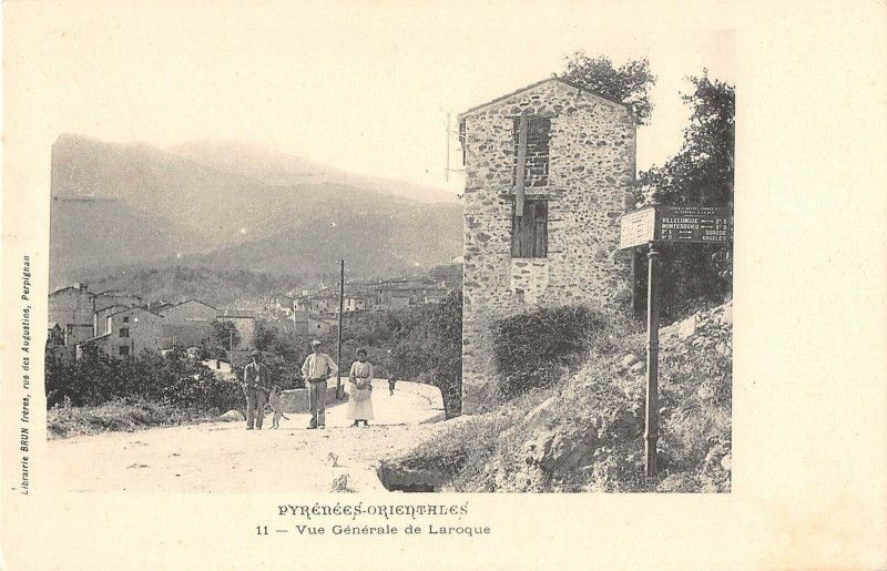 Carte postale ancienne, entrée de Laroque avec un poteau indicateur et trois passants
