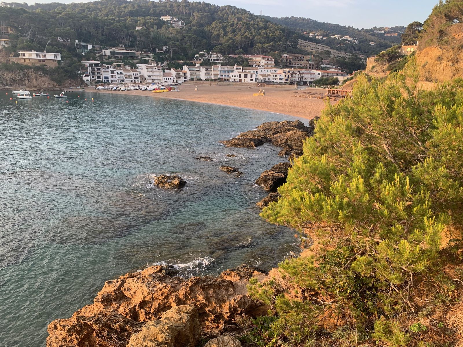 Vue plongeante sur la crique de Sa Tuna depuis le sentier, les barques au mouillage et la plage au fond